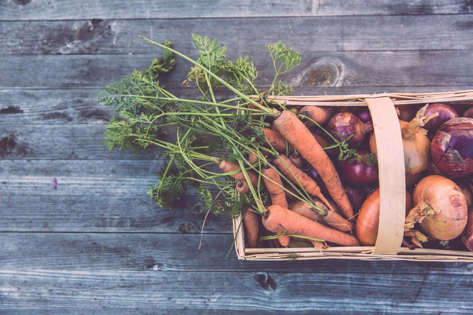 carrots and onions in brown wicker basket